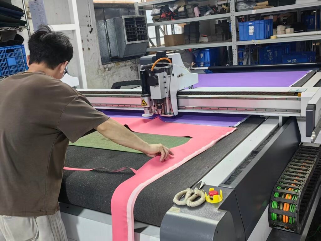 Automated material cutting for custom camera cases, preparing fabric and lining components for OEM case production.