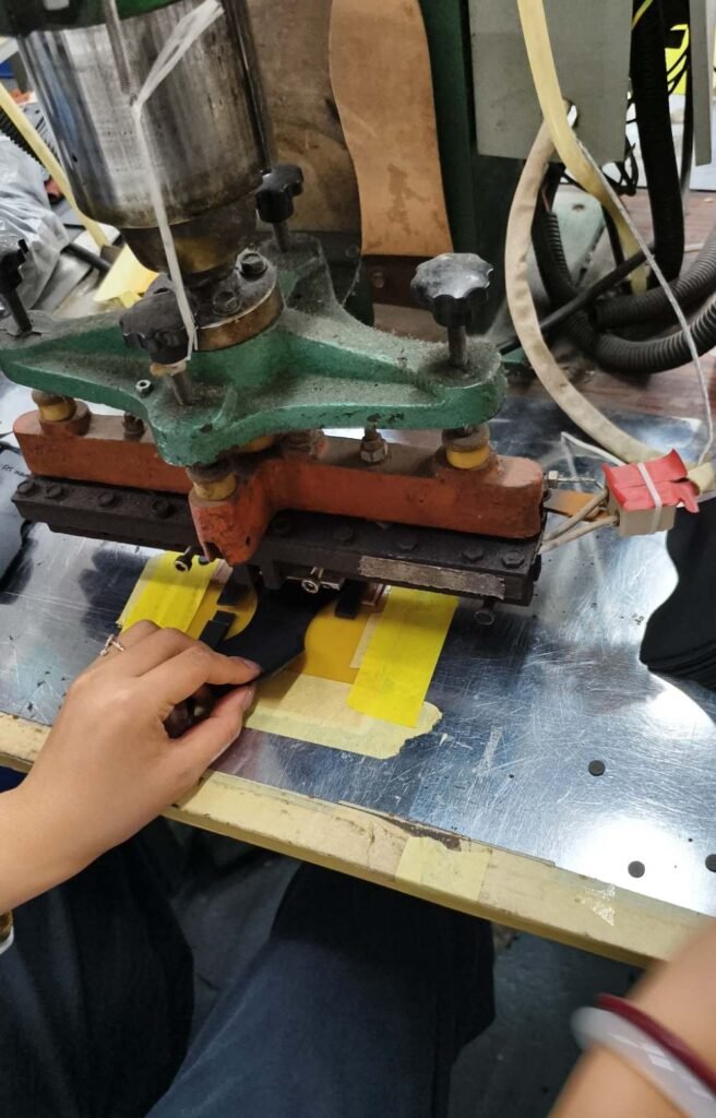 Worker heat-pressing a custom logo onto a camera case panel at an OEM factory